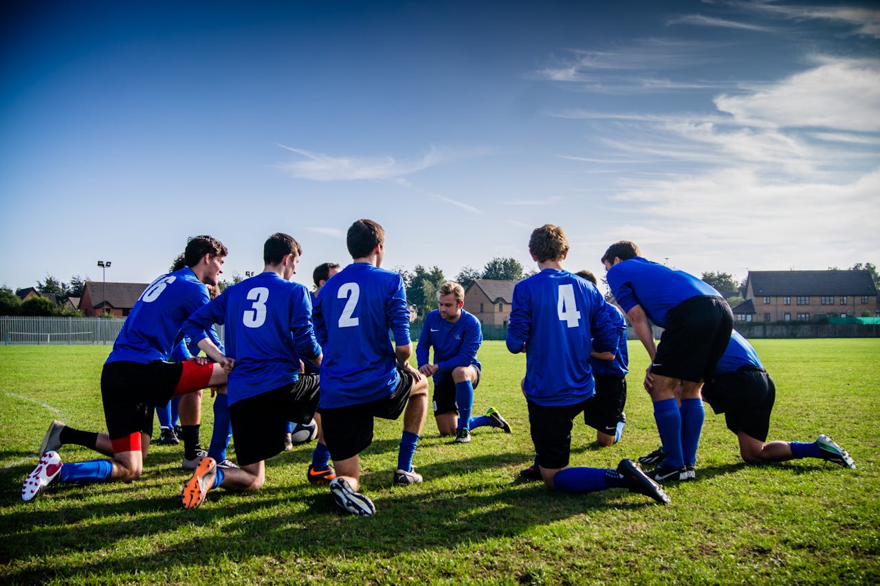 The Art of Drawing Readers In: Your attractive post title goes here A group of male football players in blue uniforms huddle on a grassy field before a match.
